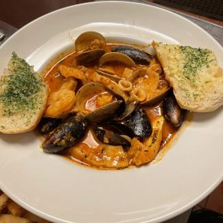 Cioppino, an Italian-American dish loaded with fresh clams, shrimp, squid rings, mussels and fish sautéed in a light tomato wine sauce served with toasted garlic bread